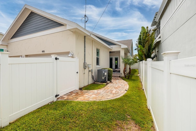 view of side of home featuring central AC and a yard