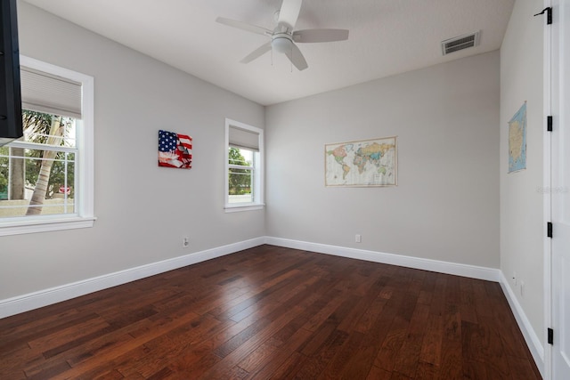 unfurnished room featuring ceiling fan, dark wood-type flooring, and a wealth of natural light