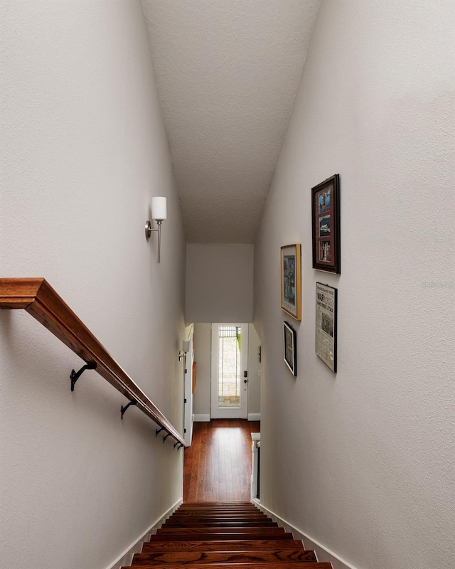 staircase featuring wood-type flooring and lofted ceiling