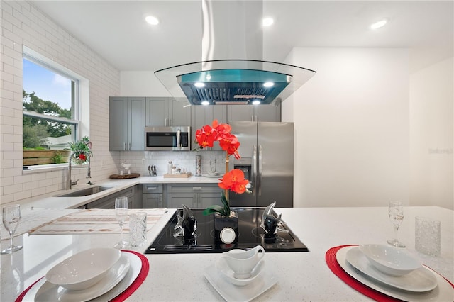 kitchen with island range hood, appliances with stainless steel finishes, sink, and gray cabinetry