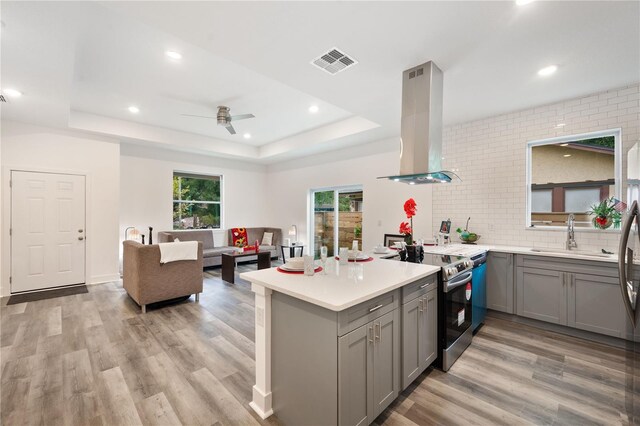 kitchen featuring light hardwood / wood-style flooring, kitchen peninsula, stainless steel electric stove, and extractor fan