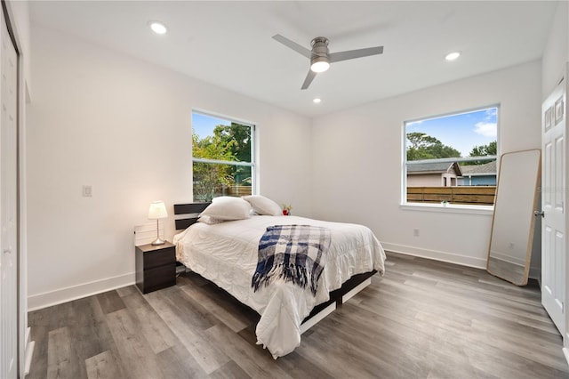 bedroom with a closet, hardwood / wood-style floors, multiple windows, and ceiling fan