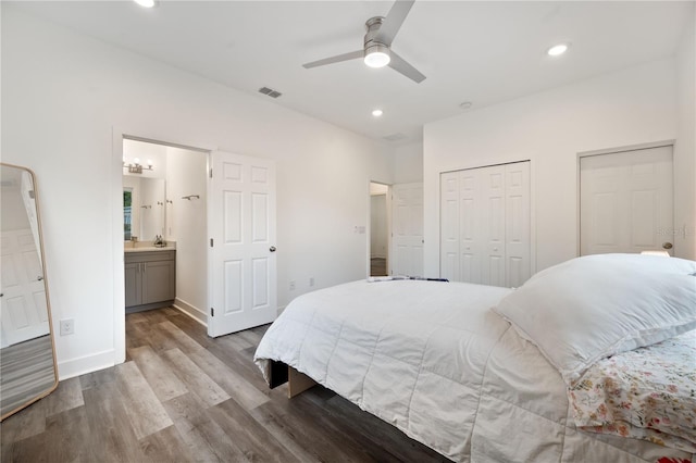 bedroom featuring light hardwood / wood-style flooring, connected bathroom, multiple closets, and ceiling fan