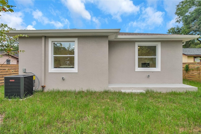 rear view of house featuring a lawn and central AC