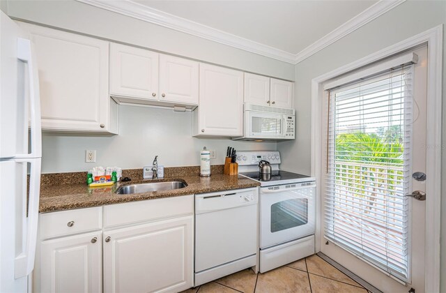 kitchen with white cabinets, light tile patterned floors, ornamental molding, sink, and white appliances