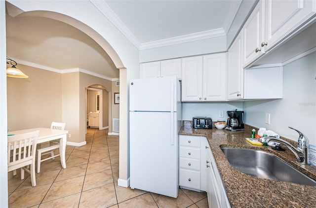 kitchen featuring white refrigerator, ornamental molding, sink, white cabinetry, and dark stone counters