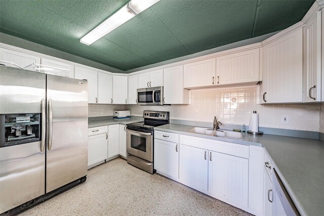 kitchen with white cabinets, sink, a textured ceiling, backsplash, and stainless steel appliances