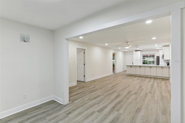 unfurnished living room featuring ceiling fan, sink, and light hardwood / wood-style floors