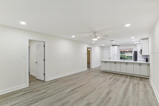 unfurnished living room with light wood-type flooring and ceiling fan