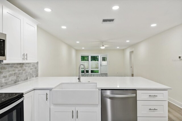 kitchen featuring kitchen peninsula, white cabinetry, ceiling fan, and stainless steel dishwasher