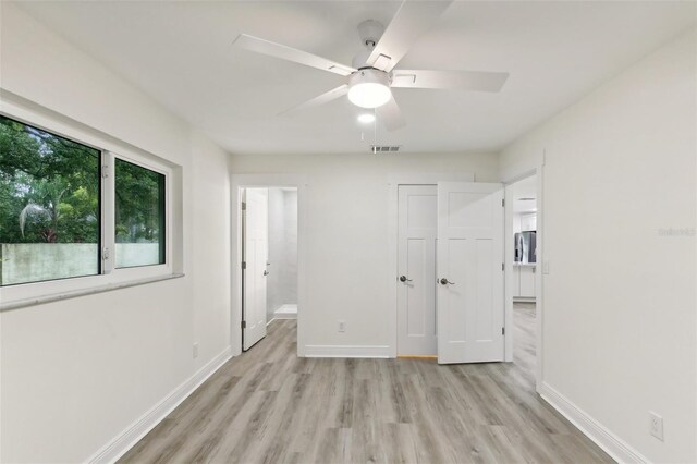 unfurnished bedroom with light wood-type flooring, ceiling fan, and connected bathroom