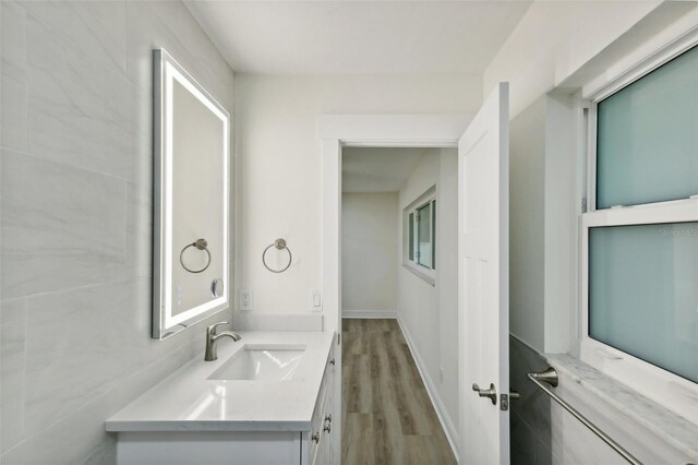 bathroom featuring wood-type flooring, vanity, and tile walls