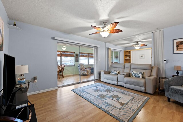 living room with light wood-type flooring, a textured ceiling, and ceiling fan