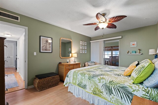 bedroom with ceiling fan, a textured ceiling, light wood-type flooring, and access to outside