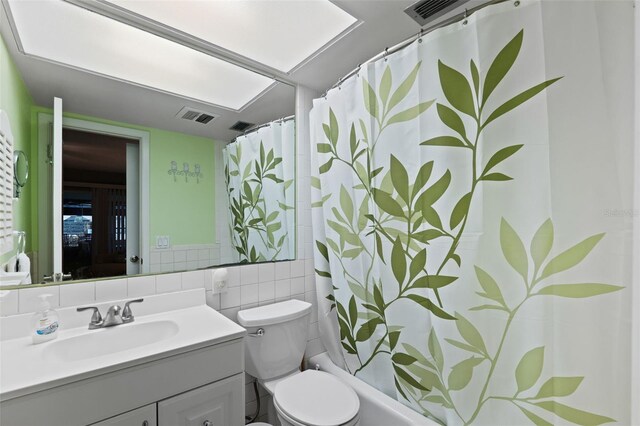 full bathroom featuring vanity, tile walls, toilet, and shower / tub combo with curtain