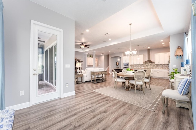 dining space featuring ceiling fan with notable chandelier, light hardwood / wood-style floors, and a healthy amount of sunlight