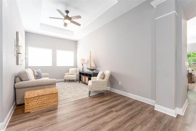 interior space with ceiling fan, a tray ceiling, and wood-type flooring