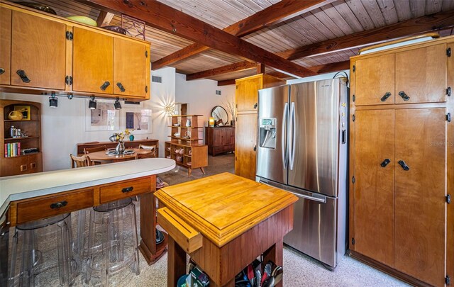 kitchen featuring beam ceiling, stainless steel refrigerator with ice dispenser, and wooden ceiling