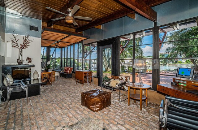 sunroom / solarium featuring ceiling fan and beamed ceiling