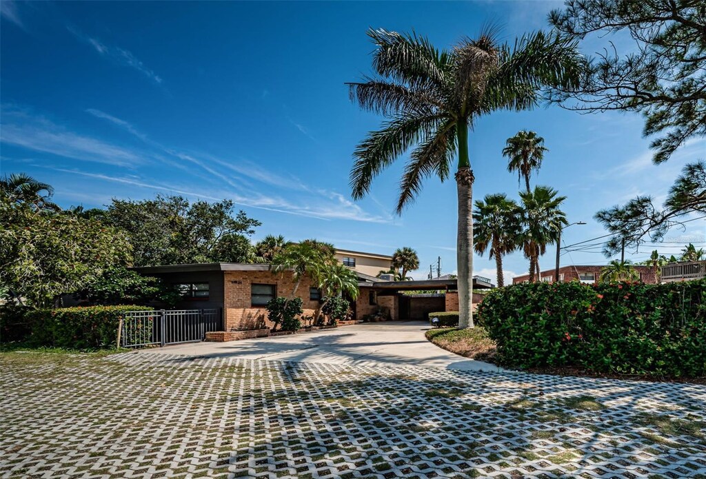view of front facade featuring brick siding, a gate, and driveway
