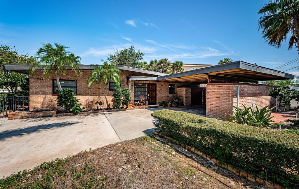 view of front of house with a carport, concrete driveway, and brick siding