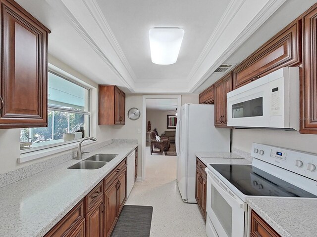 kitchen with a raised ceiling, white appliances, ornamental molding, and sink