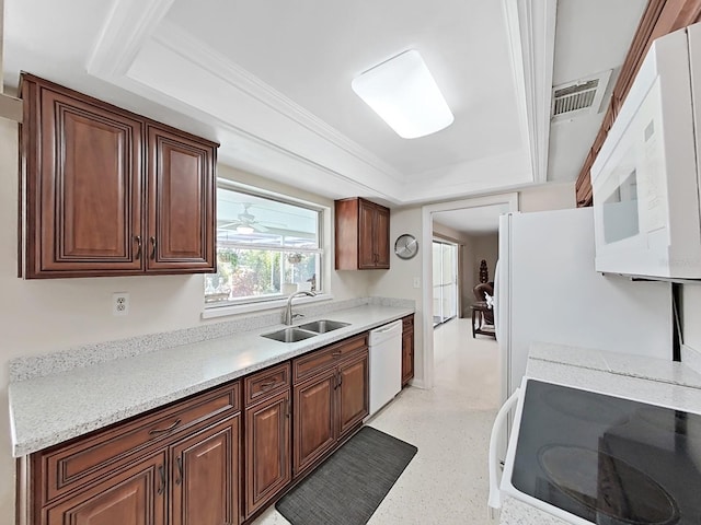 kitchen with white appliances, a raised ceiling, light stone counters, and sink