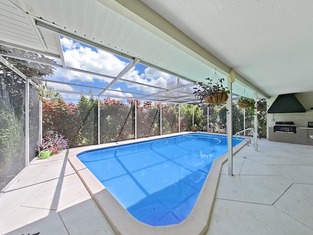 view of swimming pool with grilling area, an outdoor kitchen, glass enclosure, and a patio area