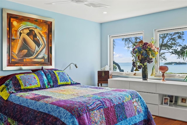 bedroom featuring ceiling fan, a water view, and hardwood / wood-style flooring