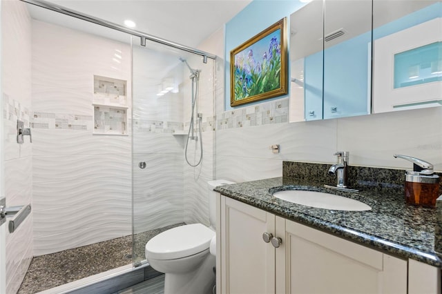 full bathroom featuring visible vents, tiled shower, toilet, vanity, and tile walls