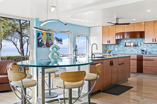 kitchen featuring decorative backsplash, a wealth of natural light, a water view, and hanging light fixtures