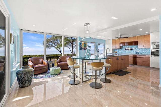 kitchen with pendant lighting, backsplash, a center island with sink, sink, and appliances with stainless steel finishes