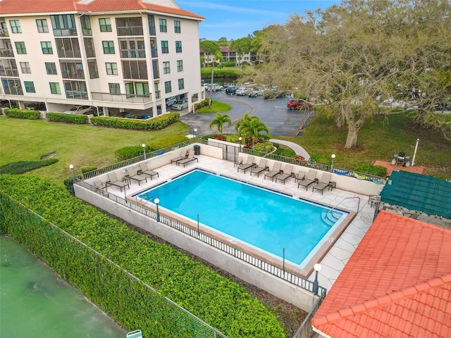 pool featuring a patio area, fence, and a lawn