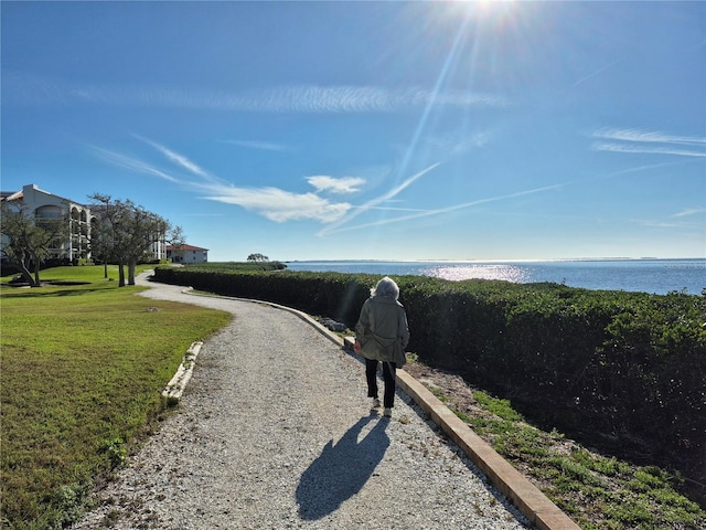 view of street with a water view and gravel driveway