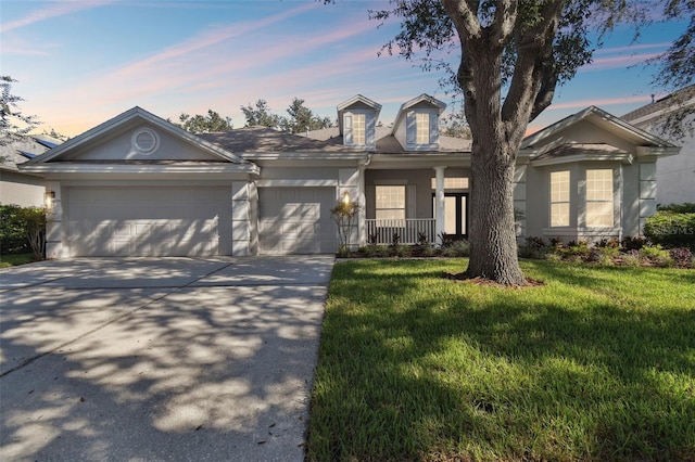 view of front of home with a garage, a lawn, and covered porch