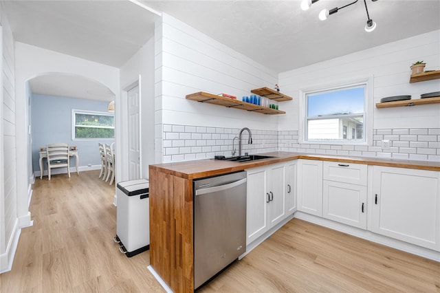 kitchen with light wood-type flooring, dishwasher, sink, white cabinets, and butcher block countertops