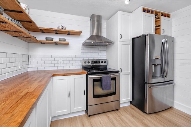 kitchen with light hardwood / wood-style floors, white cabinetry, stainless steel appliances, wood counters, and wall chimney range hood