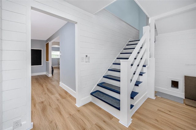 stairs with wood-type flooring and wood walls