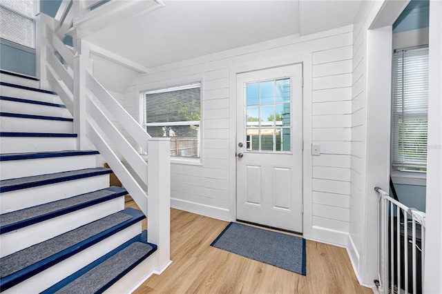 entryway with light wood-type flooring and wooden walls