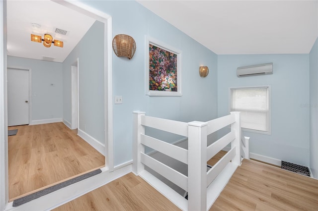 hallway with hardwood / wood-style flooring, lofted ceiling, and a wall mounted AC