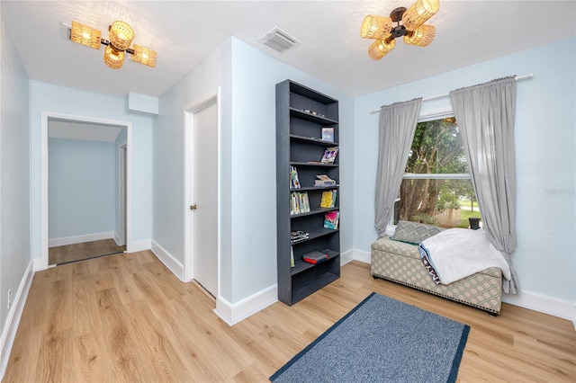 living area with an inviting chandelier and light hardwood / wood-style flooring