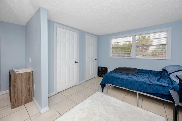 bedroom with a textured ceiling and light tile patterned floors