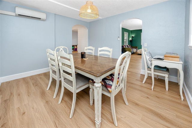 dining area featuring light hardwood / wood-style floors and an AC wall unit