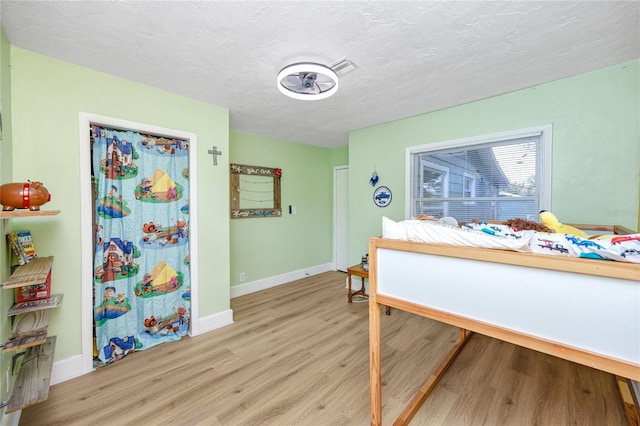 bedroom with a textured ceiling and light wood-type flooring