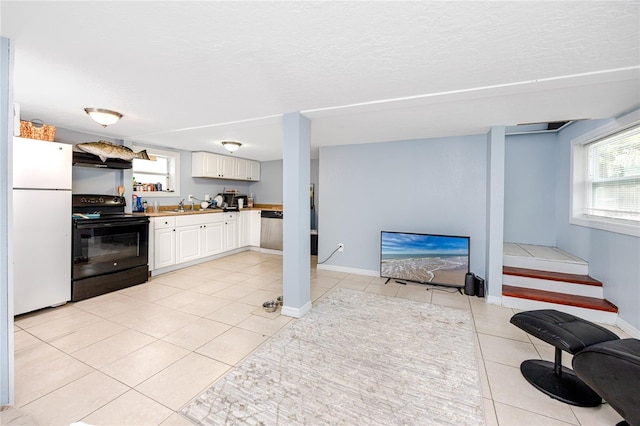6619 Livingston Ave N, Saint Petersburg, FL 33702 - kitchen with black / electric stove, plenty of natural light, light tile patterned floors, and freestanding refrigerator