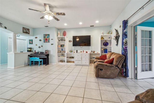 living room featuring decorative columns, light tile patterned flooring, and ceiling fan