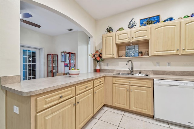 kitchen featuring a sink, arched walkways, light brown cabinets, a peninsula, and white dishwasher