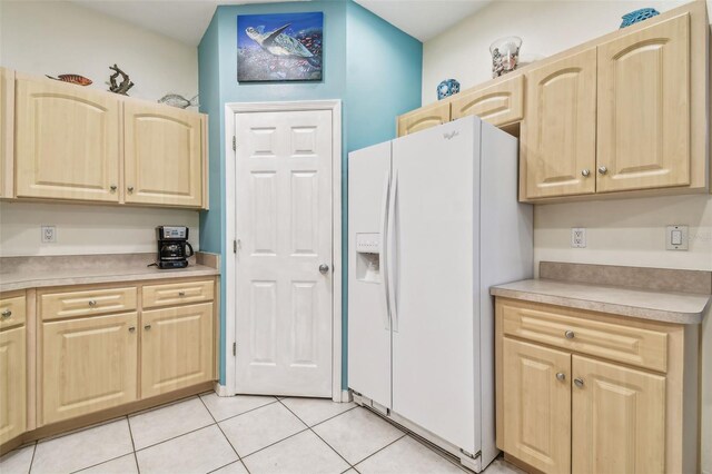 kitchen featuring white fridge with ice dispenser, light brown cabinets, and light tile patterned floors