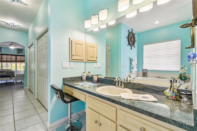 bathroom featuring ceiling fan, vanity, a textured ceiling, a bathing tub, and tile patterned flooring