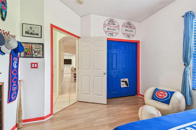 bedroom featuring light wood-style flooring, baseboards, and arched walkways